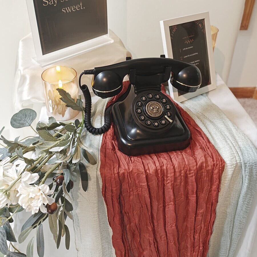 Black vintage audio guestbook phone on a terracotta runner with a framed how-it-works card
